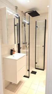 Un baño con lavabo blanco y ducha. en Modern apartment in the heart of Drammen, en Drammen