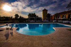 a large swimming pool with a clock tower in the background at Alloggi In Corte  +5 photos