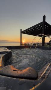 a hot tub with an umbrella and the ocean at Private beach on a fenced in property sunset views in Hampton Bays