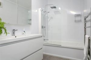 a white bathroom with a shower and a sink at Modern Townhouse, Stunning Views in Taupo +24 photos