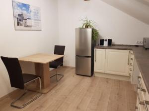 BaiersdorfにあるFurnished Apartment with kitchen and bathroom near Erlangenのテーブルとステンレス製の冷蔵庫を備えたキッチン
