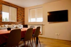a dining room with a table and a television on a wall at Къща за Гости Тодор in Shiroki Dol