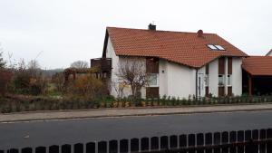 BaiersdorfにあるFurnished Apartment with kitchen and bathroom near Erlangenの道路脇の赤い屋根の白い家