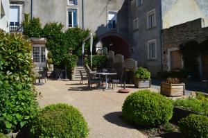 un patio con mesa y sillas frente a un edificio en Logis Le Bretagne en Sillé-le-Guillaume