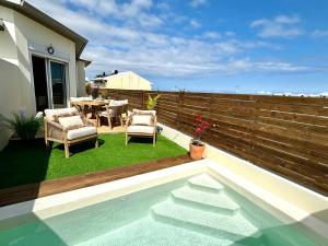 a backyard with a table and chairs and a swimming pool at Ti Cocoon by Ti Pêcheurs Vue océan in Petite Île
