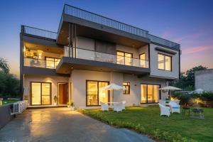 a large house with chairs and umbrellas in the yard at Gardenia 4-BHK Farmhouse with Private Pool, Game Zone, & Lush Garden in Dera Māndi +44 photos