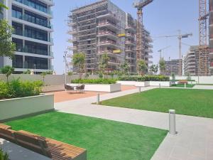 a park with benches and grass in a city at Azizi Riviera 61 - Serene Studio in Meydan in Dubai