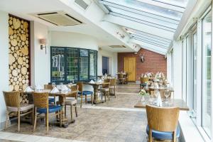 a dining room with tables and chairs and windows at Macdonald Craxton Wood Hotel & Spa in Ledsham
