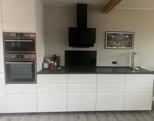 una cucina con armadi bianchi e una TV a parete di Solskinshuset a Hasle Altre 5 foto