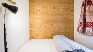 une chambre avec un lit avec une lampe et un mur en bois dans l'établissement Grande Neige N 10 - 2P4, à Morillon