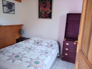 a bedroom with a quilt on a bed and a dresser at Maisonnette avec jardin - Séjour détente in Sabran