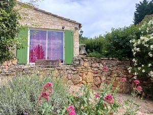 a garden with a stone wall and a green door at Maisonnette avec jardin - Séjour détente in Sabran +8 photos