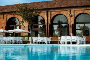 a restaurant with white tables and chairs next to a swimming pool at Alloggi In Corte in Cascina Fienili