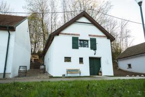 a white house with green shuttered windows and a bench at Weinfass Chalet Für 8 In Grub An Der March in Grub an der March