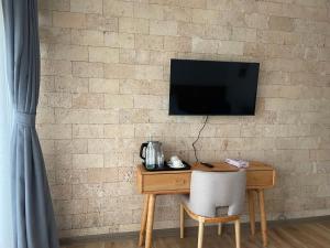 a wooden desk with a television on a brick wall at Idan Barn Suites & Café in Naro Moru
