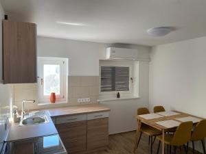 a kitchen with a sink and a table with chairs at Gerbera Apartman in Ábrahámhegy