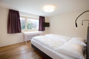 1 dormitorio con cama blanca y ventana en Schtûbat (Contactless Check-In), en Andelsbuch