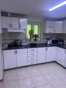 a kitchen with white cabinets and white appliances at Guesthouse IVA in Karakol