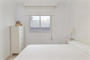 a white bedroom with a bed and a window at Casa Ricardo in Barbate