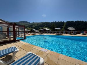 a swimming pool with chairs and a person in the water at Charmant logement avec Balnéo - La Plagne 1800 in Plagne 1800