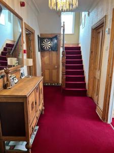 a hallway with red carpet and stairs with a mirror at Brantwood Guest House in Iford