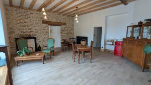 a living room with a table and chairs and a brick wall at Auberge de la Belette Cendrée in Saint-Léger-sous-Beuvray