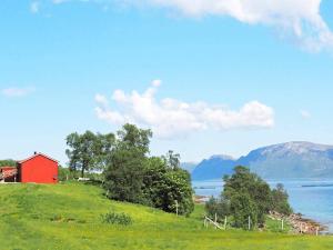 un granero rojo en una colina junto a un lago en 6 person holiday home in ALSVÅG-By Traum, en Gisløy