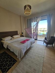 a bedroom with a bed and a chair and a window at فيلا Azha بالعين السخنه للعائلات in Ain Sokhna +15 photos