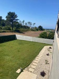 un jardin avec pelouse et mur de retenue dans l'établissement AgrelaBeach, à Marinhas