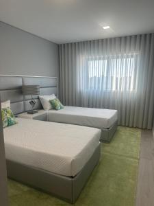 une chambre avec deux lits et une fenêtre dans l'établissement AgrelaBeach, à Marinhas