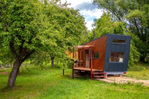 a tiny house sitting in a field next to a tree at Ráj pod Troskami in Semily
