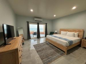 クリスチャンステッドにあるGrapetree Bay Hotel and Villasのベッドとテレビとバルコニーのある寝室