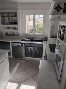 a white kitchen with a sink and a window at Villa Les Arts in Talmont