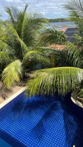 a blue swimming pool with palm trees and the ocean at Paraiso da Lagoa in Estância