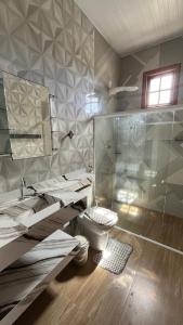 a bathroom with a toilet and a glass shower at Paraiso da Lagoa in Estância +17 photos