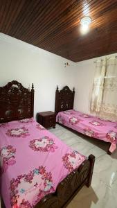 two beds in a bedroom with pink sheets at Paraiso da Lagoa in Estância