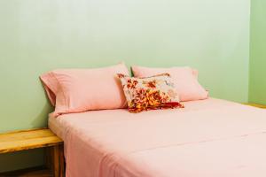 a bed with pink sheets and pillows on it at Habitación Confort Queen in Peña Blanca
