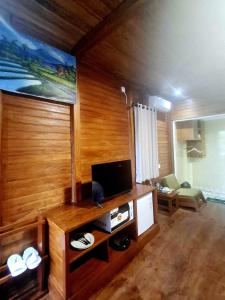a living room with wooden walls and a flat screen tv at Pondok Denly by Pigeon in Nusa Dua
