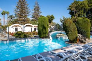 a swimming pool with chairs in front of a house at Bungalows Cordial Biarritz in Playa del Ingles