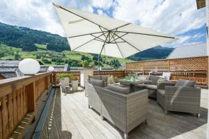 a patio with chairs and an umbrella on a deck at Hotel Krone Großarl in Grossarl