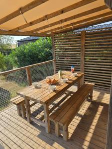 a wooden picnic table on a deck with an umbrella at Mobil Home Cosy Plage à 50 m Camping 5 in Torreilles