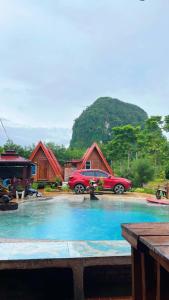 Un coche aparcado delante de un grupo de chozas en Thanya local campsite Thailand, en Ban Thai Thai