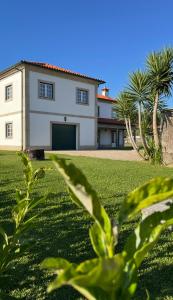 a large white house with palm trees in front of it at Cantinho do Minho - Ponte de Lima in Ponte de Lima