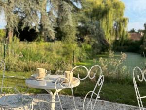 a table and chairs with cups on top of it at La Meslaysienne - Comfortable house, swimming pool in Meslay-le-Vidame