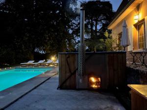 a fireplace next to a swimming pool at night at La Meslaysienne - Comfortable house, swimming pool in Meslay-le-Vidame