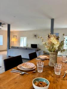 a table with plates of food and a vase of flowers at Le Douare, Proche centre-ville, Parking in Morestel