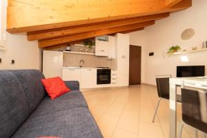Una sala de estar con un sofá azul y una cocina. en Rho Fiera Home, graziosa e confortevole, con parcheggio interno privato gratuito, en Rho