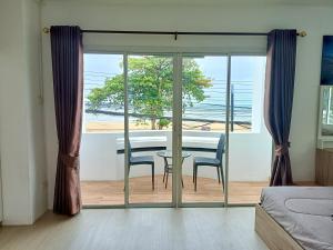 a bedroom with a table and chairs and a view of the ocean at Beach front B3 Marie Guest house in Jomtien Beach