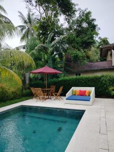 a pool with a table and chairs and an umbrella at LaGita Carita Beach Villa 2 in Carita