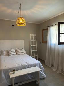 een slaapkamer met een wit bed en een kroonluchter bij Casita de Barrio in Lobos